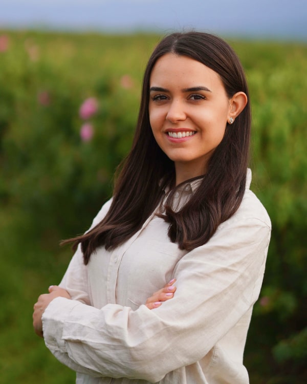 A stunning young woman smiles brightly in a vibrant field filled with colorful flowers, radiating joy and beauty.